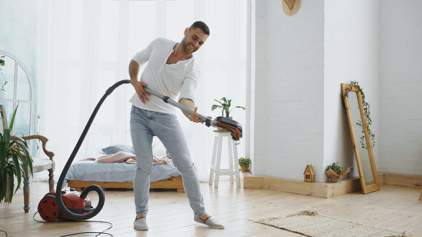 Man happily vacuuming and playing guitar with vacuum cleaner